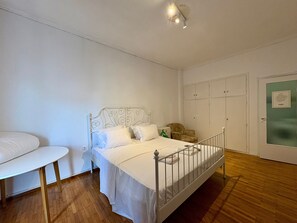 A single-bed room with a white metal headboard, a small bedside table, a chair, and a wardrobe with a green door. - Apartment 'Dear Greece I Miss You' with Wi-Fi and Air Conditioning (Kallithea)