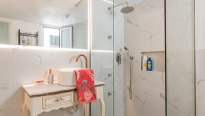 Une salle de bain avec un lavabo en marbre, une cabine de douche en verre et un meuble-lavabo avec un miroir.
