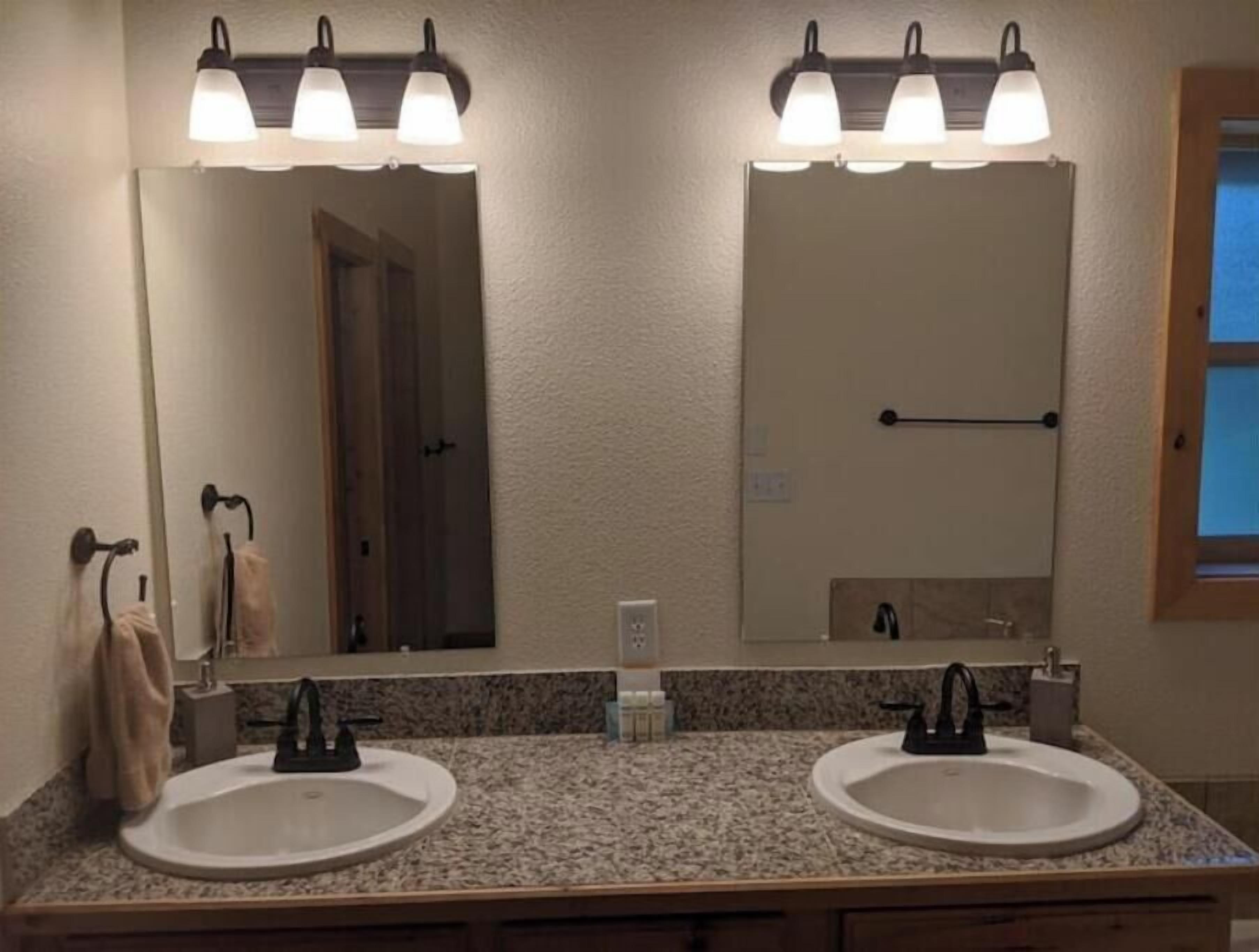 A bathroom with two sinks, a mirror, and a towel rack.