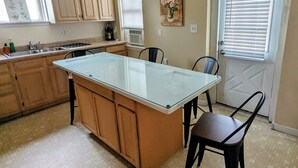 Une cuisine avec des meubles en bois, un îlot central en verre et un coin repas avec des chaises.