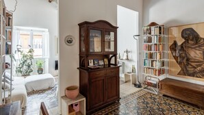 A cozy living room with a wooden cabinet, a bookshelf, and a large painting. - Fori Imperiali Amazing Terrace (Roma)
