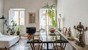 A cozy living room with a glass dining table, comfortable seating, a TV, and decorative items. - Fori Imperiali Amazing Terrace (Roma)