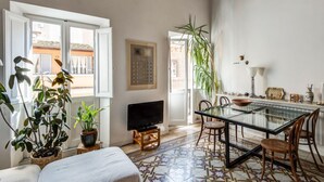 A cozy living room with a TV, a glass dining table, and various plants. - Fori Imperiali Amazing Terrace (Roma)