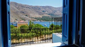A balcony with a view of a coastal town, a mountain range, and a body of water with boats. - Apartment 'Irene Family' with Sea View, Wi-Fi and Air Conditioning (Symi)