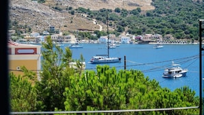 A coastal town with boats docked in a marina, surrounded by residential buildings and a hilly landscape. - Apartment 'Irene Family' with Sea View, Wi-Fi and Air Conditioning (Symi)
