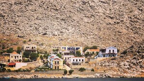 Un poble costaner amb cases construïdes sobre un turó, amb vista a una massa d'aigua.