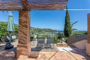 Eine Terrasse mit Gartenmöbeln, einer Pergola und Meerblick.