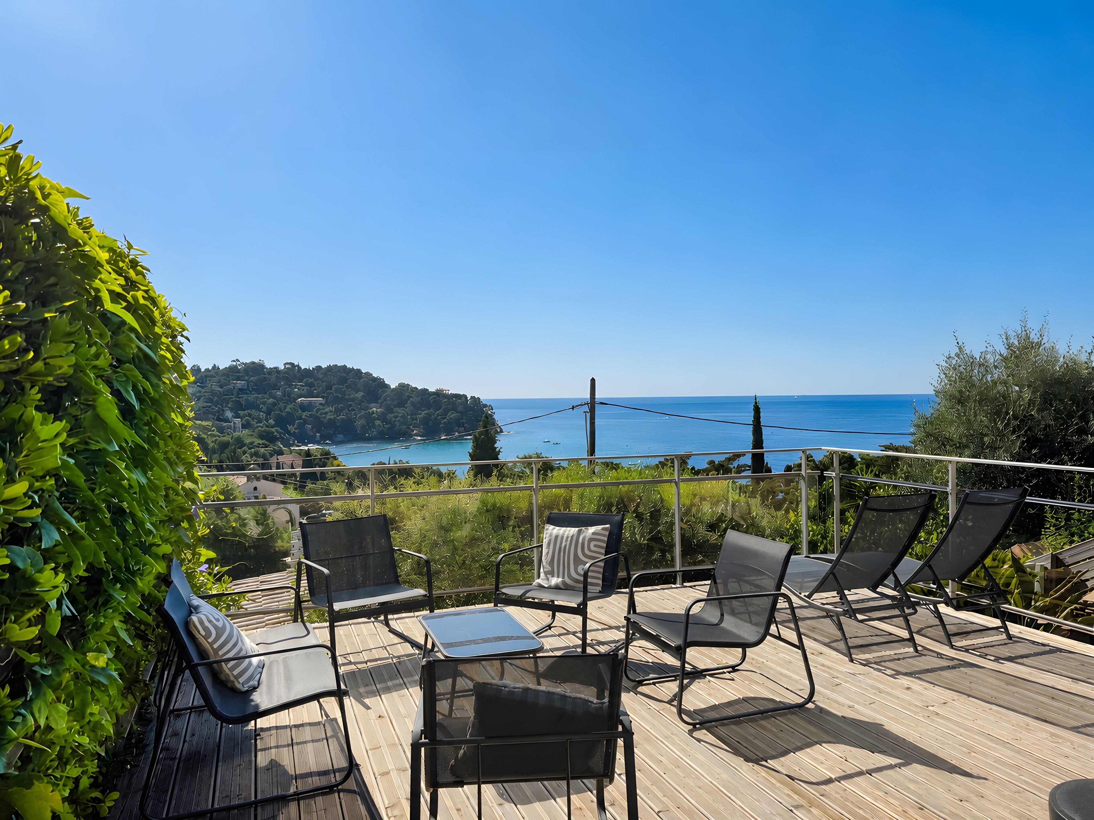 A deck with outdoor seating and a view of the sea.