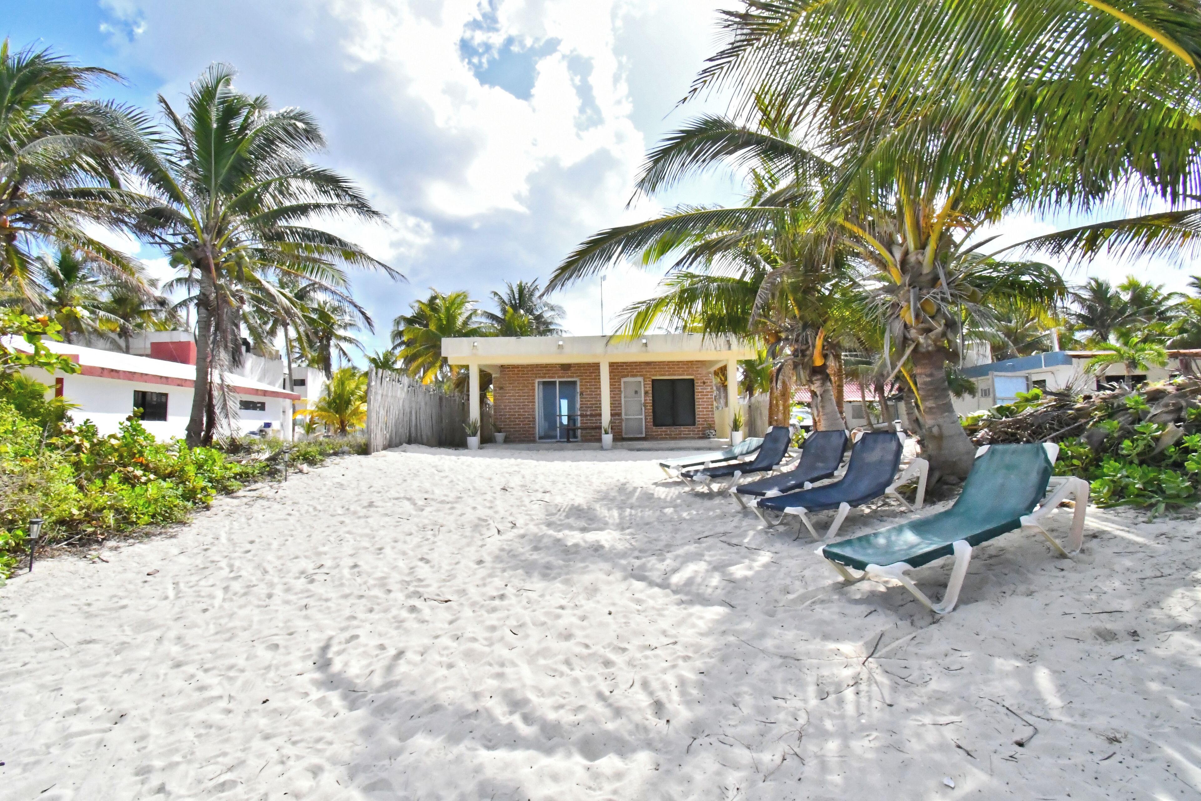 Pantai pribadi, pasir putih, kursi berjemur, dan handuk pantai