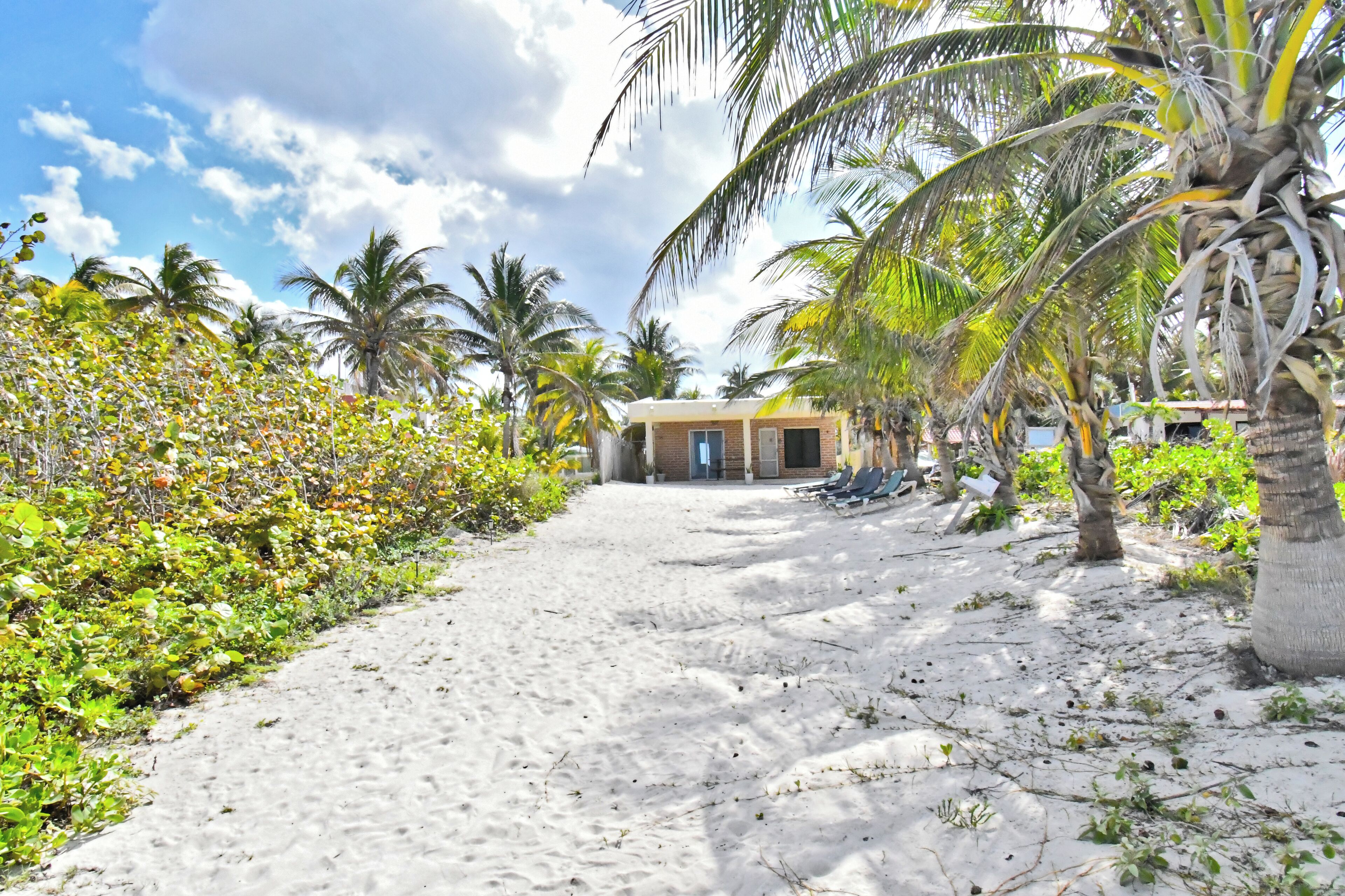 Pantai pribadi, pasir putih, kursi berjemur, dan handuk pantai