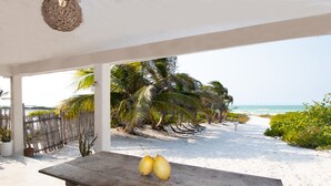 A wooden table with two coconuts on it, overlooking a beach with palm trees and a clear view of the ocean. - Arena y Mar Beachfront House, El Cuyo by The Spot Rentals (Tizimín)