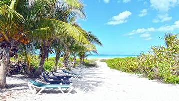 Praia particular, areia branca, espreguiçadeiras, toalhas de praia