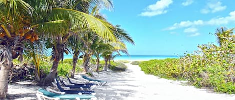 Aan een privéstrand, wit zand, ligstoelen, strandlakens