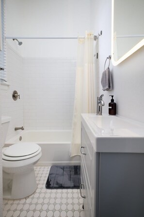 Une salle de bain avec des toilettes blanches, une baignoire, un lavabo et un miroir.