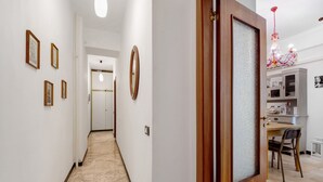 A hallway with framed pictures on the wall, a wooden door with frosted glass, and a dining area with a chandelier. - Apartment 'Lulu' with Private Terrace, Wi-Fi, Convenient for Cinque Terre and Portofino (Lavagna)