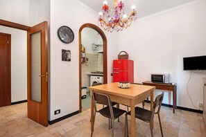A dining area with a table, chairs, a red refrigerator, a microwave, and a television on a stand.