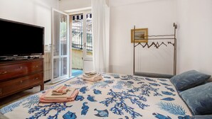 A bedroom with a bed, a dresser, a television, a radiator, a window with curtains, and a metal rack with clothes. - Apartment 'Lulu' with Private Terrace, Wi-Fi, Convenient for Cinque Terre and Portofino (Lavagna)