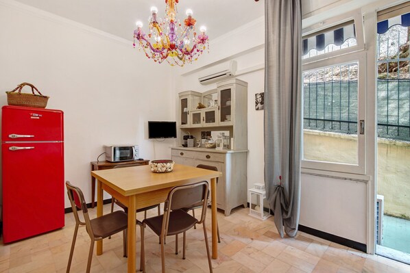 A compact kitchen with a red refrigerator, a microwave, and a dining table with chairs.