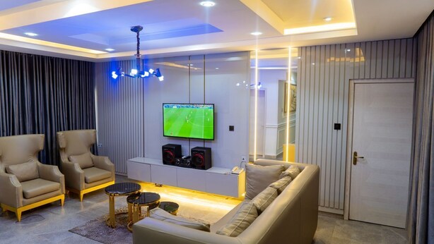 Un soggiorno moderno con un divano, due poltrone, una TV e un impianto stereo.