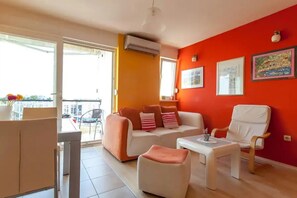 Relax in this airy living room with a sliding glass door leading to a balcony offering views of the surrounding area.