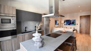 A modern kitchen with a central island, built-in appliances, and a dining area with wooden stools. - Hacienda Tuk by The Spot Rentals (Tulum)