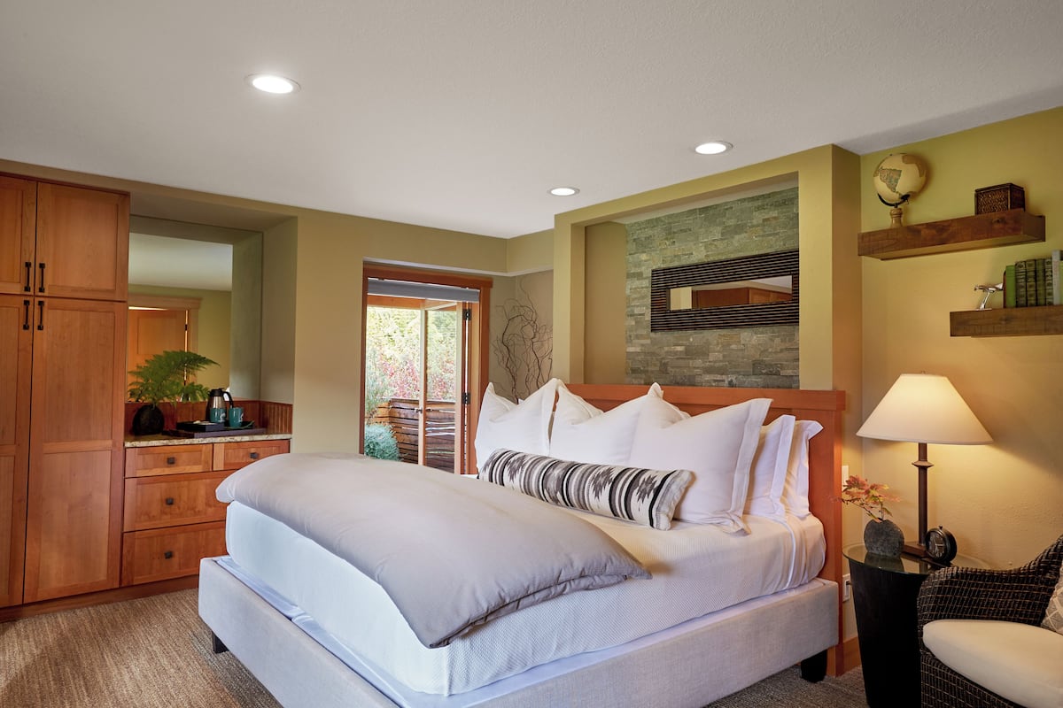 Un dormitorio con una cama grande, armarios de madera, una pared de acento de piedra y vistas al exterior.