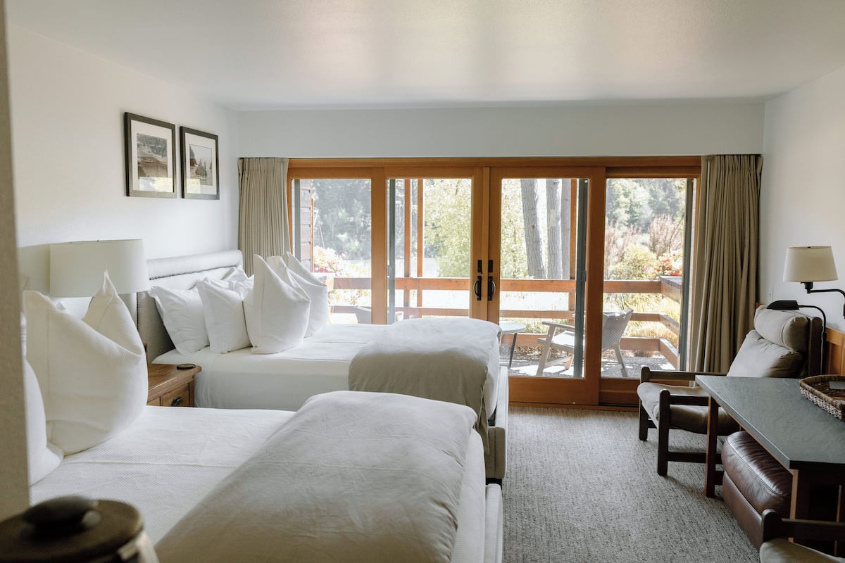 Habitación de hotel con dos camas, un escritorio y vistas al exterior.