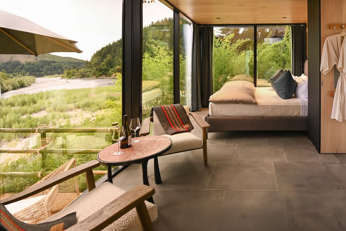 Una habitación acogedora con una cama, una mesita y una silla, con vistas a un paisaje exuberante.