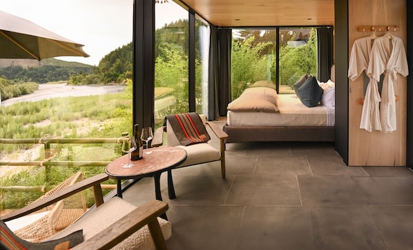 Una habitación acogedora con una cama, una mesita y una silla, con vistas a un paisaje exuberante.
