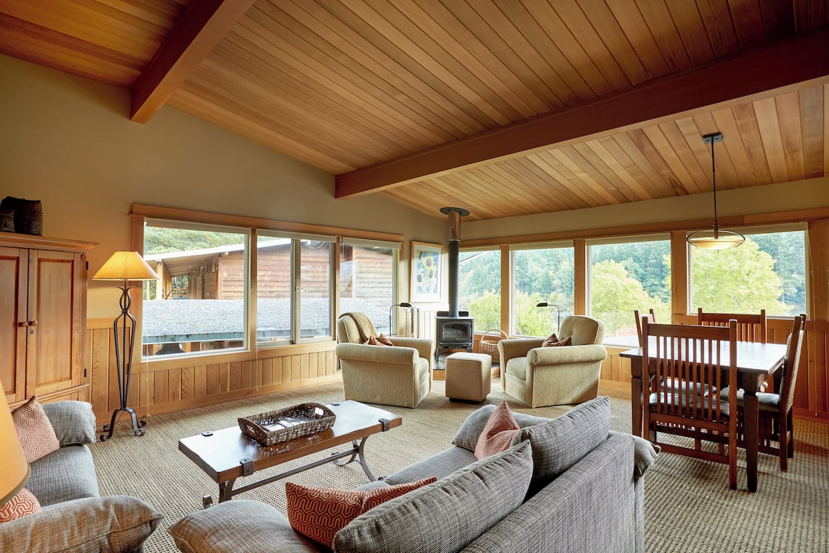 Una sala de estar acogedora con chimenea, asientos cómodos y grandes ventanas que ofrecen vistas al exterior.