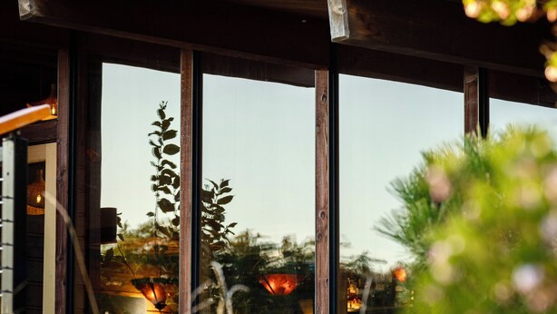 A modern building with large windows, wooden beams, and a seating area with cushions. - Tu Tu'tun Lodge (Gold Beach)