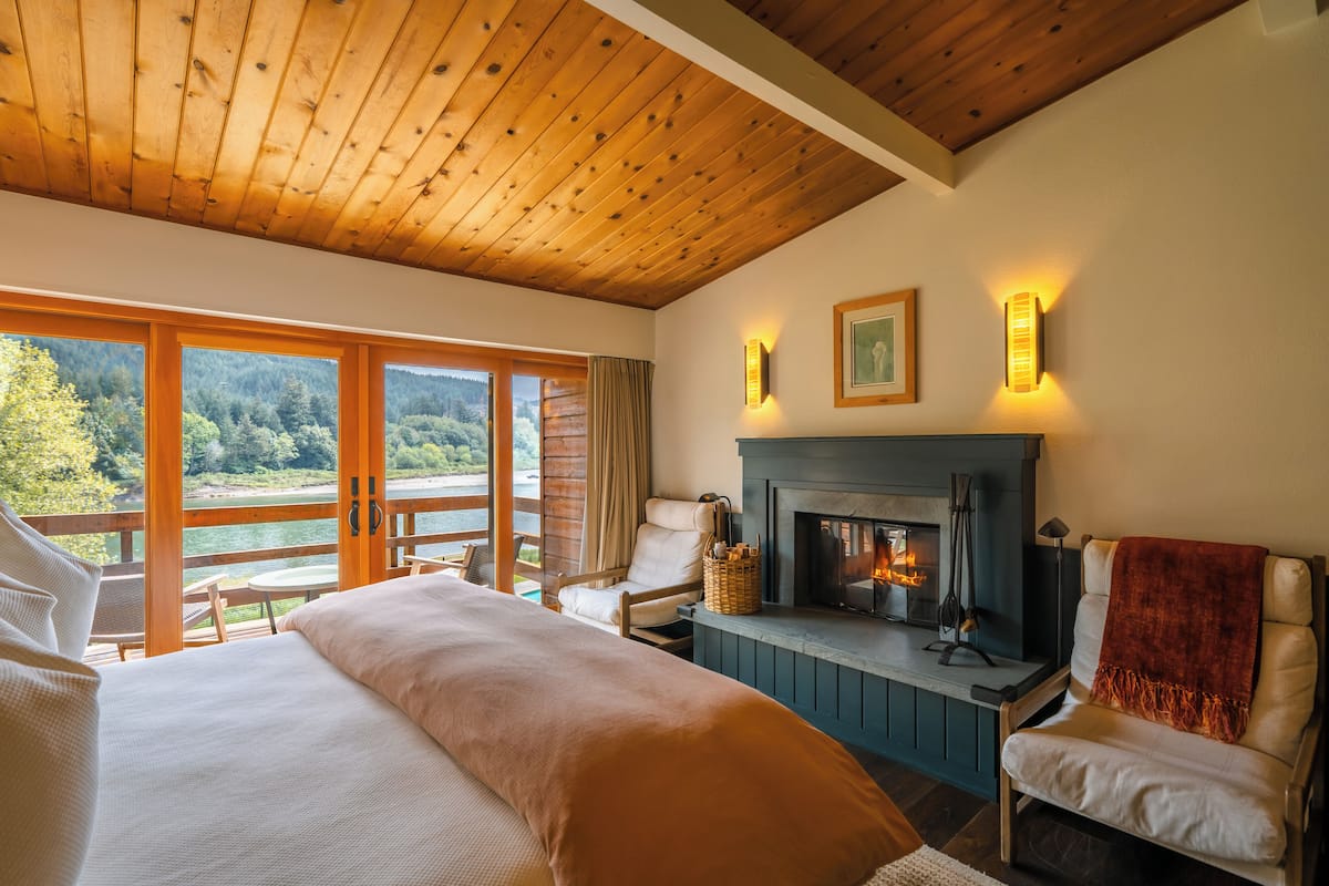 Un dormitorio con una cama grande, chimenea y vista al lago.