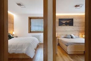 A bedroom with two beds, a window, a radiator, and a painting on the wall. - Apartment 'Casa Elisabeth' with Mountain View, Shared Garden and Balcony (Cavalese)