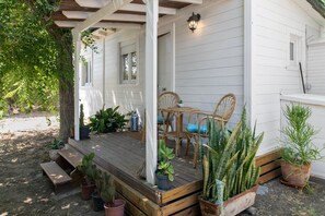 Une véranda abritée, avec des bancs en bois, des fauteuils en osier et des plantes en pot.