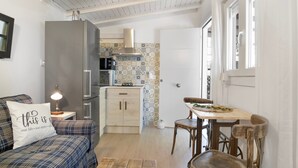 Un espacio habitable compacto con kitchenette, comedor y sofá con cojín decorativo.