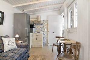 A compact living space with a kitchenette, a dining area, and a sofa with a decorative pillow. - Holiday Home 'Tiny House La Loma' with Private Terrace and Private Garden (Barbate)