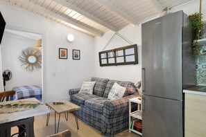 En kompakt opholdsstue med sofa, bord, køleskab og et vindue.