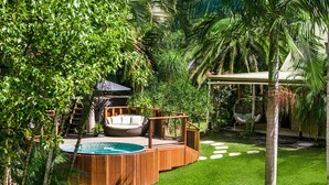Un área de piscina con terraza de madera, una silla de descanso y una hamaca.