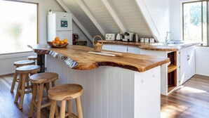 Una cocina moderna con una isla de madera, taburetes de bar y un techo alto con vigas a la vista.