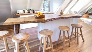 Eine moderne Küche mit Kücheninsel und Barhocker, ausgestattet mit einer schrägen Decke und großen Fenstern.