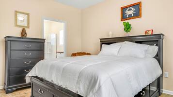Un dormitorio con cama, cómoda y puerta que da a otra habitación.