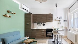 Eine moderne Küche mit Holzschränken, ein Essbereich mit Hockern und eine Sitzecke mit einer Couch.