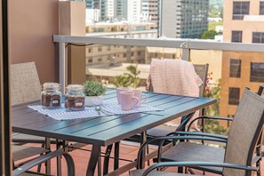 A balcony with a table set for two, featuring two jars, a small potted plant, and two pink mugs. - 3BR Townhome condo in Downtown/Free Pkg/Washer/Dryer/Huge Patio/Pool (Honolulu)