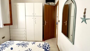 Un dormitorio con cama, armario, televisor, espejo y decoración con una estrella de mar.
