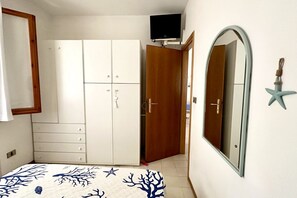 A bedroom with a bed, a wardrobe, a television, a mirror, and a starfish decoration.
