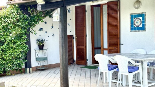 Un patio con una mesa, sillas, una planta en maceta y una pared decorada con estrellas.