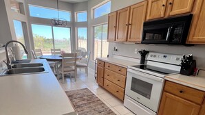 A modern kitchen with wooden cabinets, a white countertop, a built-in microwave, and a stove. - Desert Oasis / Heated Pool / Spring Training / Barrett-Jackson / WM Phoenix Open (Surprise)