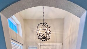 A hallway with a white door, a black doormat, and a chandelier. - Desert Oasis / Heated Pool / Spring Training / Barrett-Jackson / WM Phoenix Open (Surprise)