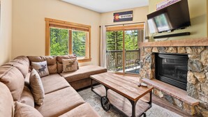 A cozy living room with a sectional sofa, a wooden coffee table, a stone fireplace, and a television mounted above it. - Expedition Station lodge at River Run Village, steps to gondola, pool, and gym

 (Keystone)