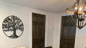 Un comedor con una mesa redonda de madera, sillas de cuero negro, una mesita auxiliar y un adorno de árbol en la pared.